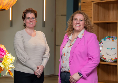 Twee glimlachende vrouwen in werkomgeving